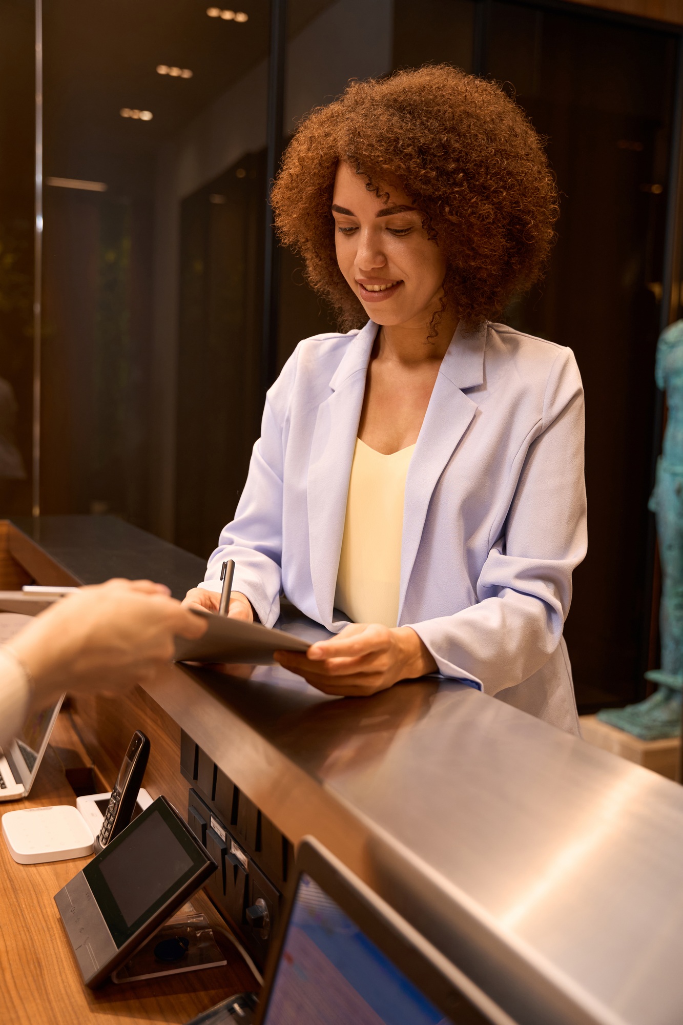 African woman filling out registration form at front desk